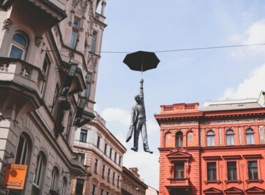 Umbrella Man Statue Praga - O sculptură captivantă a unui bărbat care ține în mână o umbrelă, suspendată în aer pe străzile din Praga, creată de artistul ceh Michal Trpák.